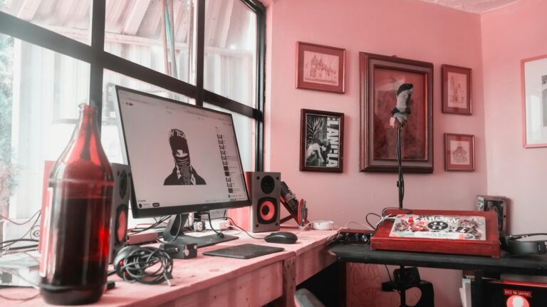 Setup Guides and Gear Reviews Home studio in a small room with a computer, speakers, microphone and framed art on the walls, no fixed acoustic panels